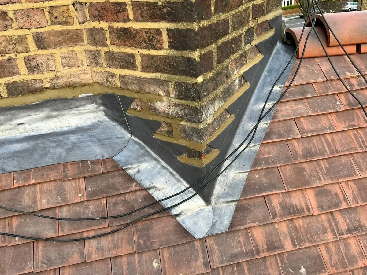 Lead flashing overview at a chimney-to-roof junction on a tiled roof
