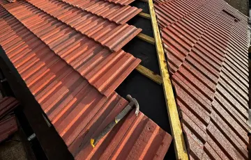 Red profiled roof tiles being installed over visible membrane and battens in Dorking