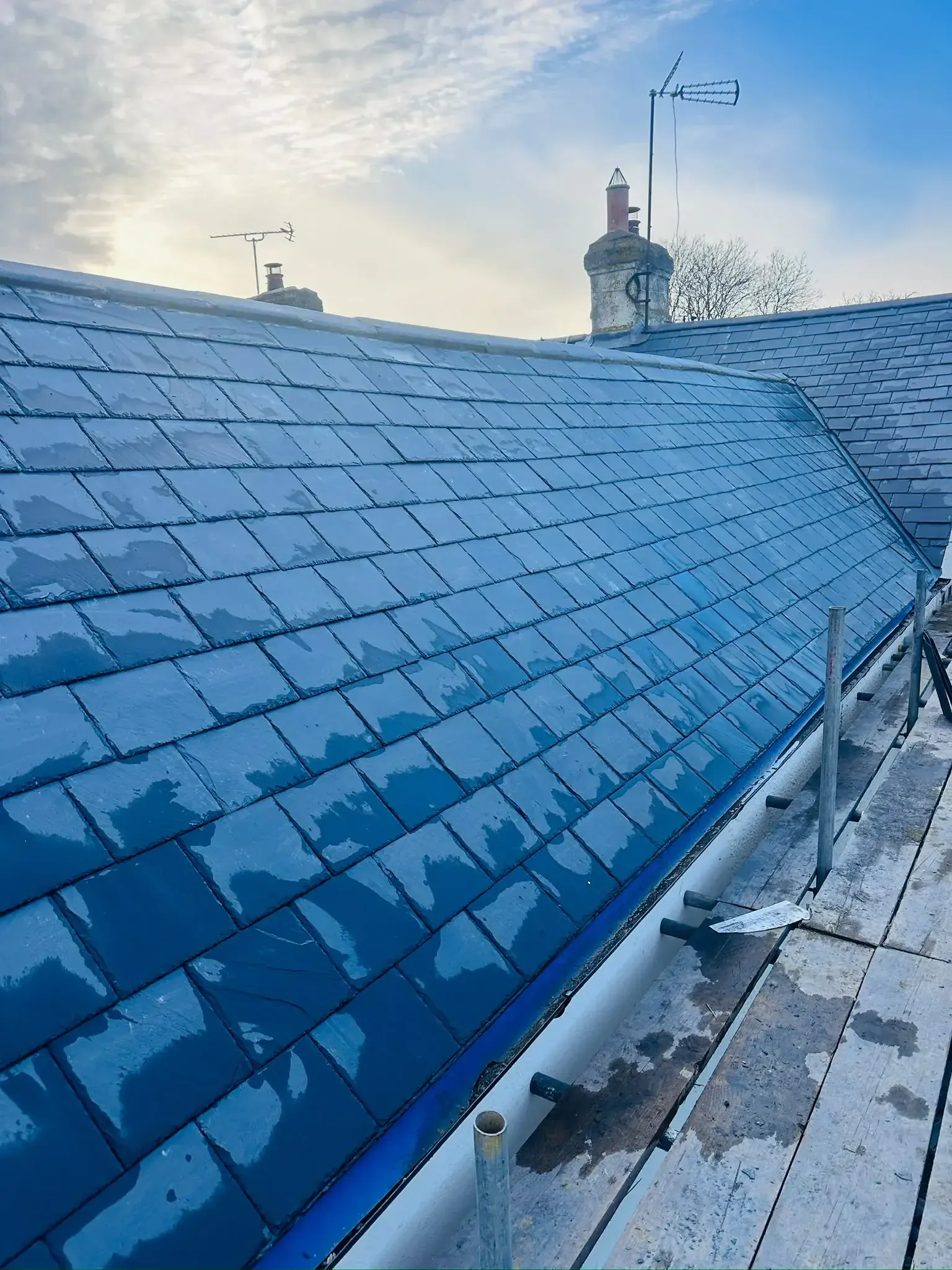 Overlapping slate-format roof covering across pitched roof slopes in Leatherhead