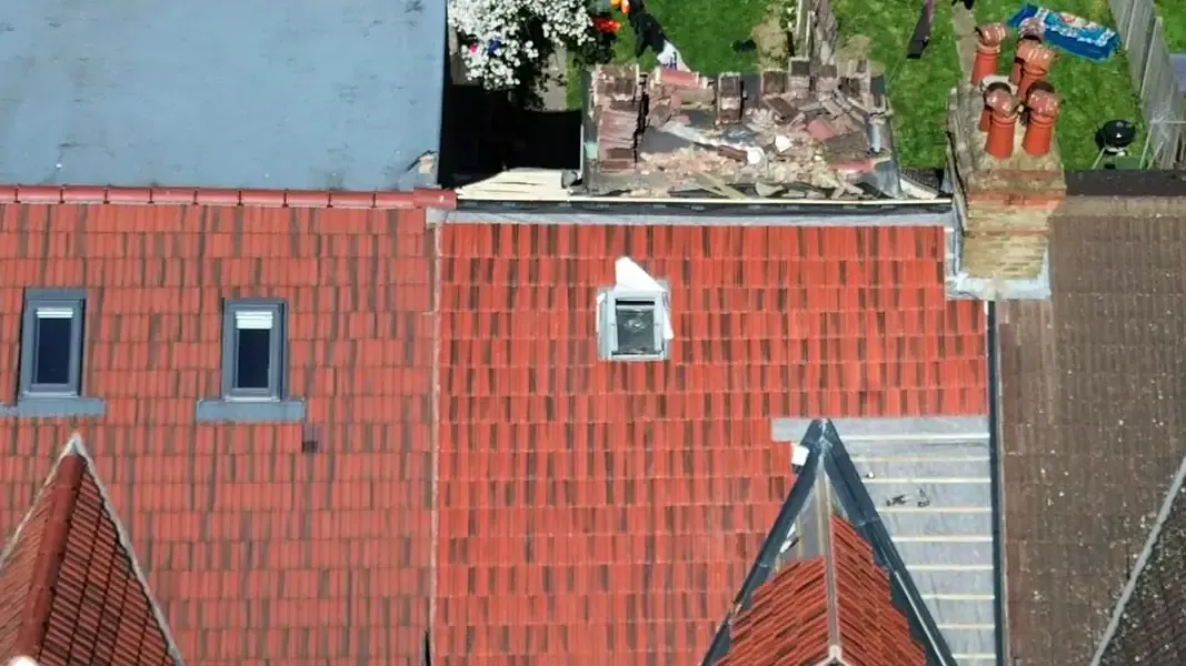 Red roof tiles beside exposed membrane and battens at a pitched roof junction in Reigate