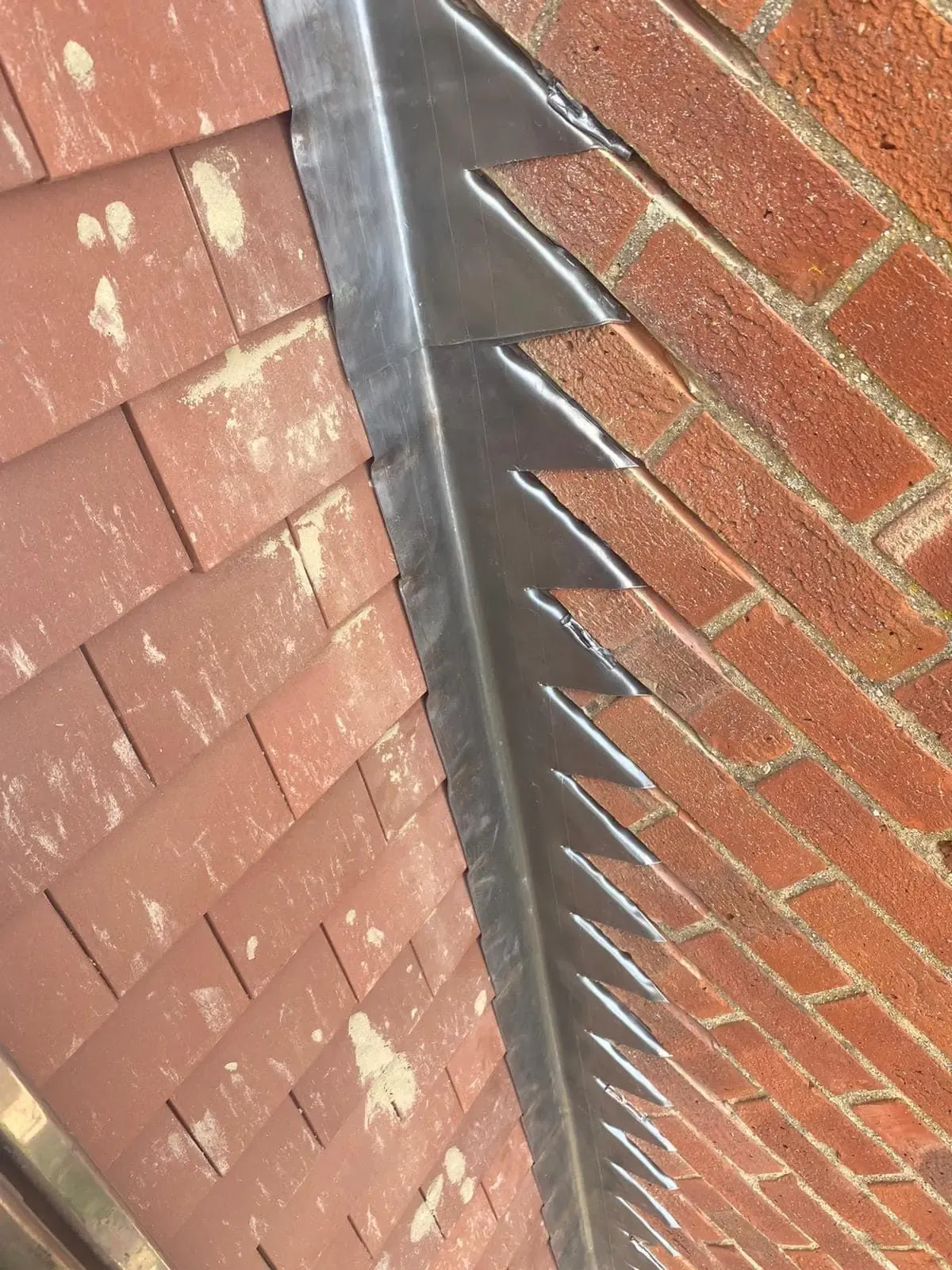 Close-up of stepped lead flashing against a brick wall